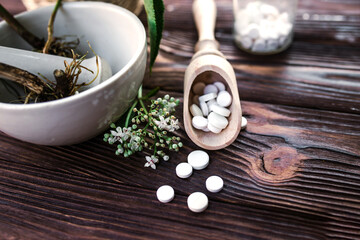 Valerian tablets with sedative properties. Pharmaceutical jar with pills on a wooden table. Cooking Valerian Root in a Mortar for Herbalism Elixirs. Soft focus