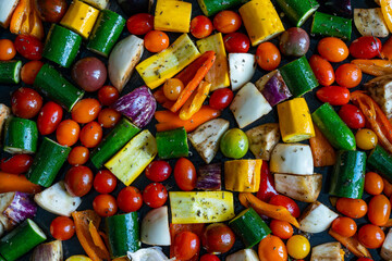 des petits légumes de toutes les couleurs découpés et éparpillés sur une plaque 
