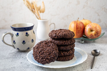 Vegan chocolate oatmeal cookies on a plate with cup of tea. Homemade and healthy baking concept.