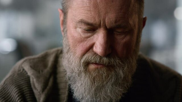 Old man face closeup. Portrait senior man thinking strategy game at home