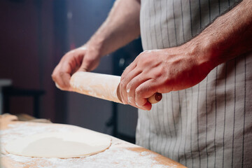 hands roll the dough into a thin layer. Cooking pizza, noodles or pitta at home