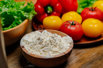 a wooden bowl of flour and vegetables on the kitchen table. farm products