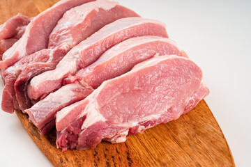 chopped into pieces raw pork on a wooden cutting board on a white background.