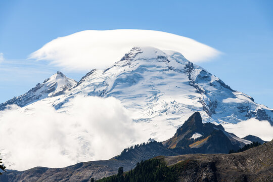 A cloud cap weather phenomenon hovers above the glacial peak of the volcanic Mount Baker in Washington State