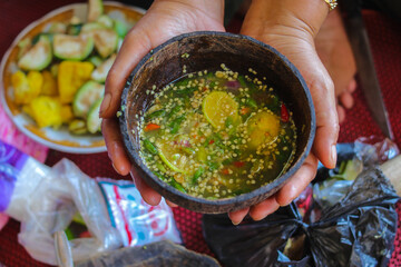 Sambal Jahe or spicy ginger sauce on wood coconut mortar (cobek) with ingredients, green chilies,...