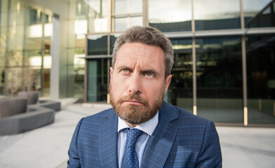 Obraz premium confused face of entrepreneur in businesslike suit outside the office, sadness