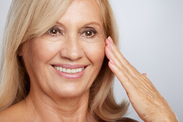 Close up of a beautiful senior lady touching her soft wrinkled skin. Beauty photography