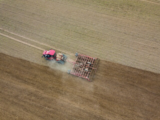 Aerial photo of a tractor ploughing stubble field in countryside. Agricultural tractor plows soil...