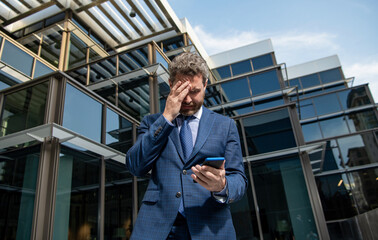 bankruptcy of sad mature business man in formalwear holding phone outdoor, anxiety