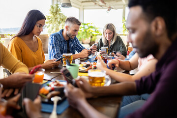 Group of young multicultural friends using smartphone while having breakfast in a cafeteria - Addiction to new technology trends concept - Focus on caucasian guy