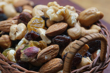 lose view of basket with dried fruits (pistachio, raisins, almonds, peanuts, walnuts) wooden board