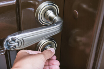 Hand locking a brown door using a knob for safety and privacy, home security concept