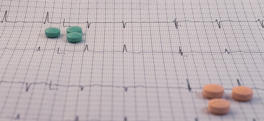Electrocardiogram written on graph paper. Pills on a cardiovascular path.