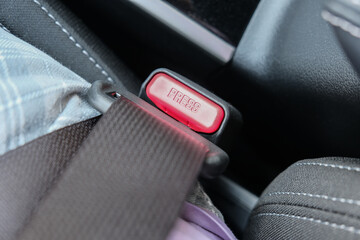 Fastened buckle and a red button of a safety belt, seatbelt in car, traffic regulations concept