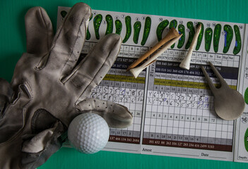 Golf score card of a mess of a game with tee's, torn golve and tools, close-up,