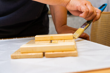 Girl varnishes a wooden detail.