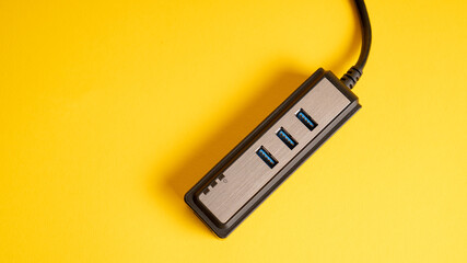 Black USB hub isolated on yellow. Three ports USB charger