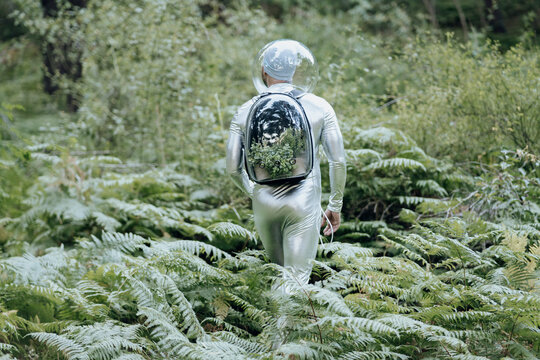 Male environmentalist with protective suit and glass backpack walking in forest