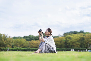 Obraz premium 公園で写真を撮るカメラ女子