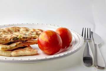 Sliced flatbread with cheese and herbs on a white plate