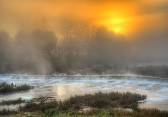 Beautiful sunrise in autumn morning. River Venta waterfall in the fog, Kuldiga, Latvia.