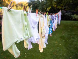 Baby cute clothes hanging on the clothesline outdoor. Child laundry hanging on line in garden.