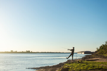 Fototapeta na wymiar Man casting his fishing rod at the edge of the river.