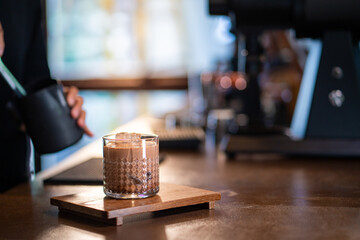 Fototapeta na wymiar Asian woman barista serving iced chocolate with froth milk to customer on bar counter at cafe. Female coffee shop waitress employee taking order from client. Small business coffee shop owner concept