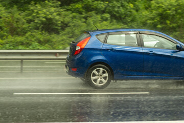 The car is driving on a wet road. Slippery road after rain. Splashes from under the wheels of transport. Rain on the highway.
