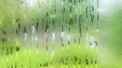 Drops of water on the glass. Condensation background of water droplets flow marks on window in coffee shop with blurred background. Selective focus