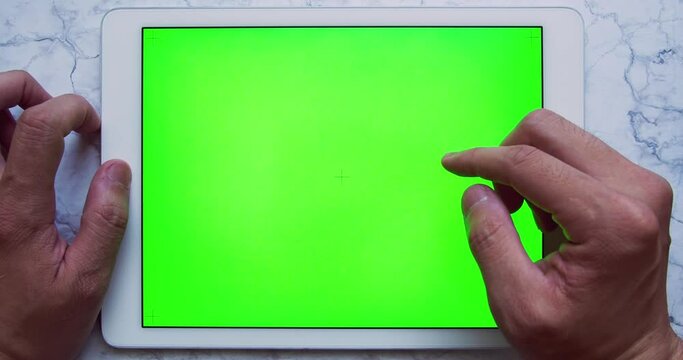 Man hands using tablet with Green Screen chroma key on marble table (touch, scroll and swipe). Mockup design at office in deco, minimal and elegant mood. Dev remote work and e-learning mock up concept