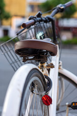 Closeup look of a white modern and vintage good looking bicycle parking on the sidewalk in Japan. With brown seat and black handle.