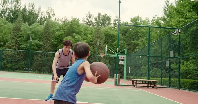 Father and son playing basketball in park,4K