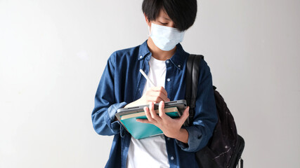 Young asian campus student man wearing protection mask while online study digital tablet in campus, coronavirus prevention in university, social distancing, online learning
