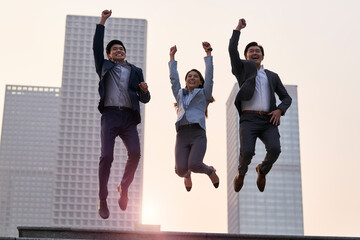three asian business people jumping and celebrating success outdoors