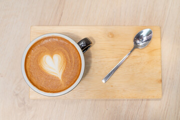 Latte coffee or cappuccino coffee in black cup with beautiful heart latte art on wooden table., Top view of latte coffee