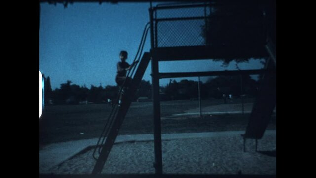 Child On A Slide 1977 - A young boy climbs and uses a slide. 