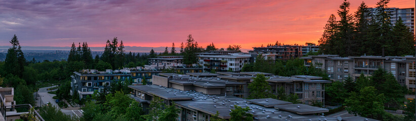 Vivid sunset over rooftops of townhomes and low-rise condos at Univercity Highlands on Burnaby...