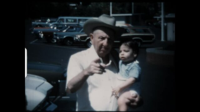 Grandfather Holds Grandson 1974 - A cowboy hat wearing grandfather holds his grandson. 