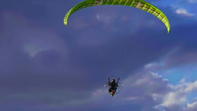 Motorized paraglider passing by at the beach