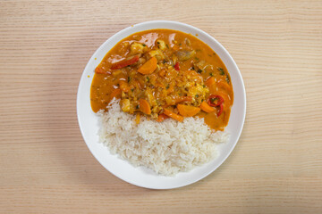 A plate of rice with chicken and vegetable curry.
