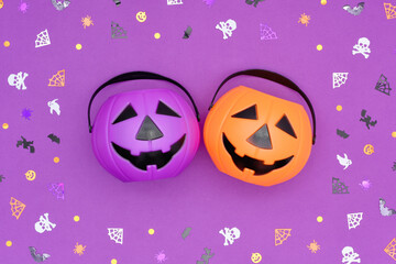 Happy Halloween concept. Jack O' Lantern Halloween pumpkin pails on purple background. Orange and...