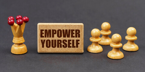 On a black background, chess and a sign with the inscription - EMPOWER YOURSELF