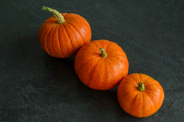 New autumn harvest bright orange pumpkins on text dark background