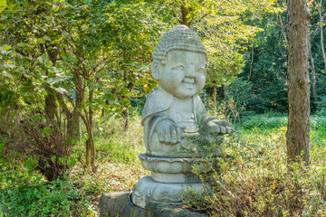 Stone carved seated buddha under shade trees