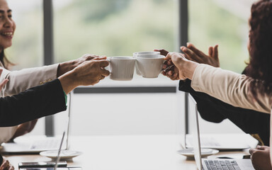 Closeup shot of cups of coffee in hands of businesswoman colleague group in formal business clothing cheering toasting together after finish meeting planning discussing strategy and target in company