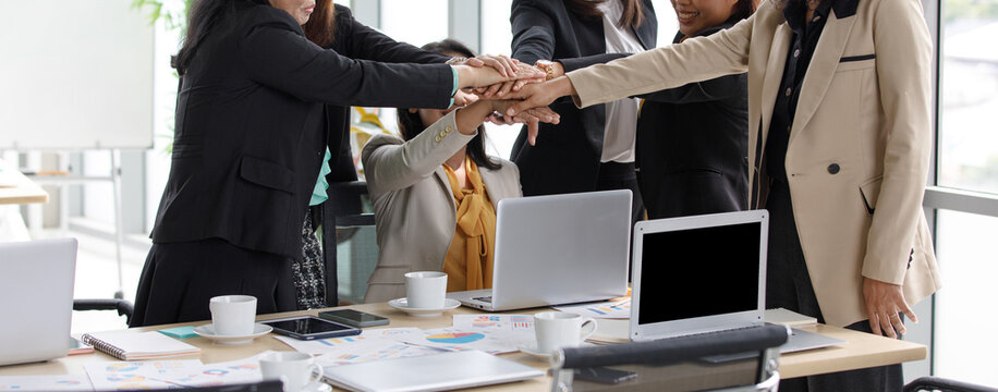 Group of unidentified unrecognizable successful female businesswoman in casual business wears standing holding hands together empower as teamwork partnership commitment agreement in company office