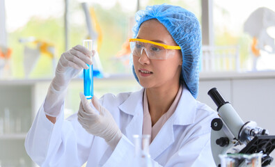 Asian female professional scientist in white lab coat safety glasses hygiene cap and rubber gloves...