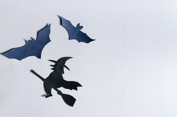 The shadow of a black witch on a broom surrounded by bats on a colored background. The layout of...
