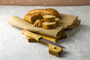 two fresh rye buns on burlap one of the buns is cut next to a knife